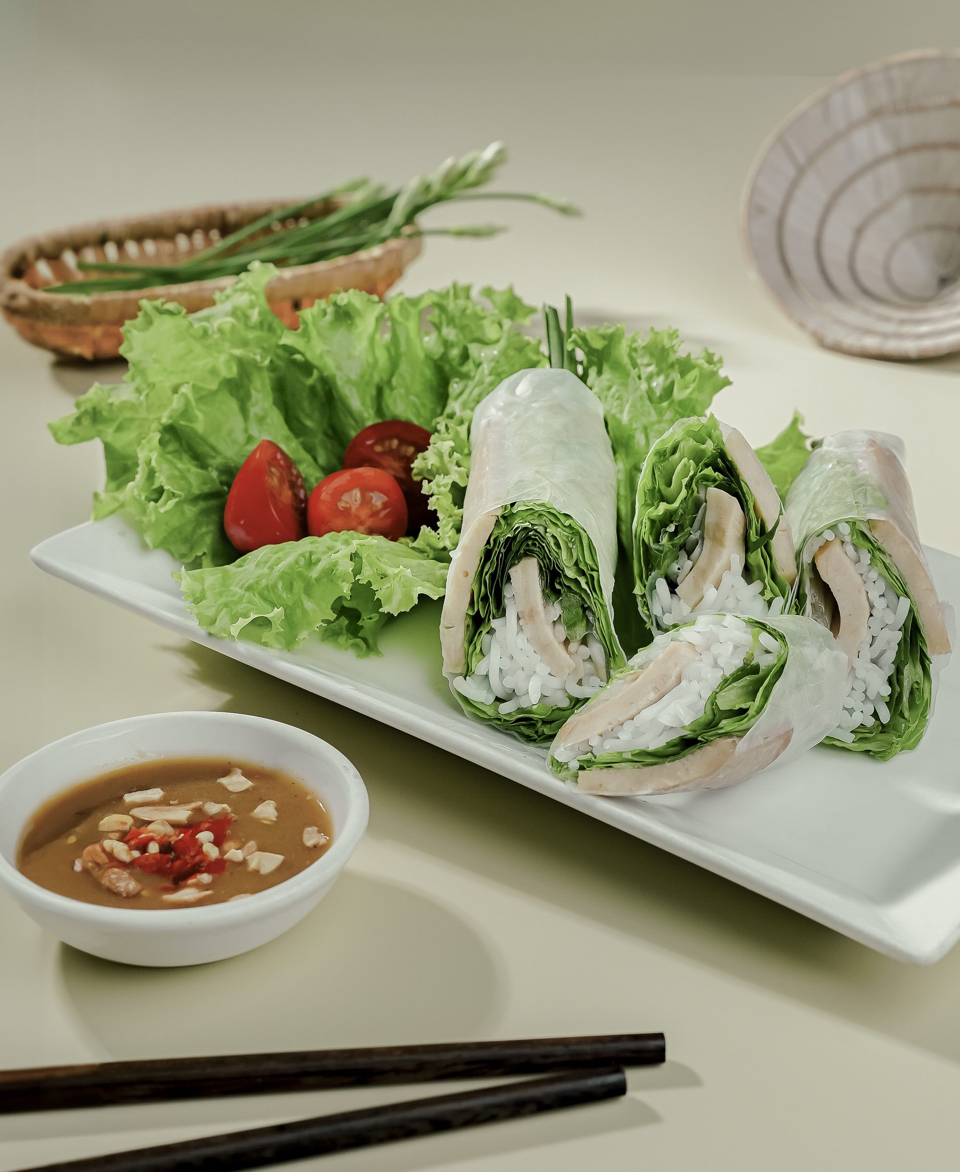 Bánh ướt cuộn trên dĩa trắng với xà lách và sốt chấm
