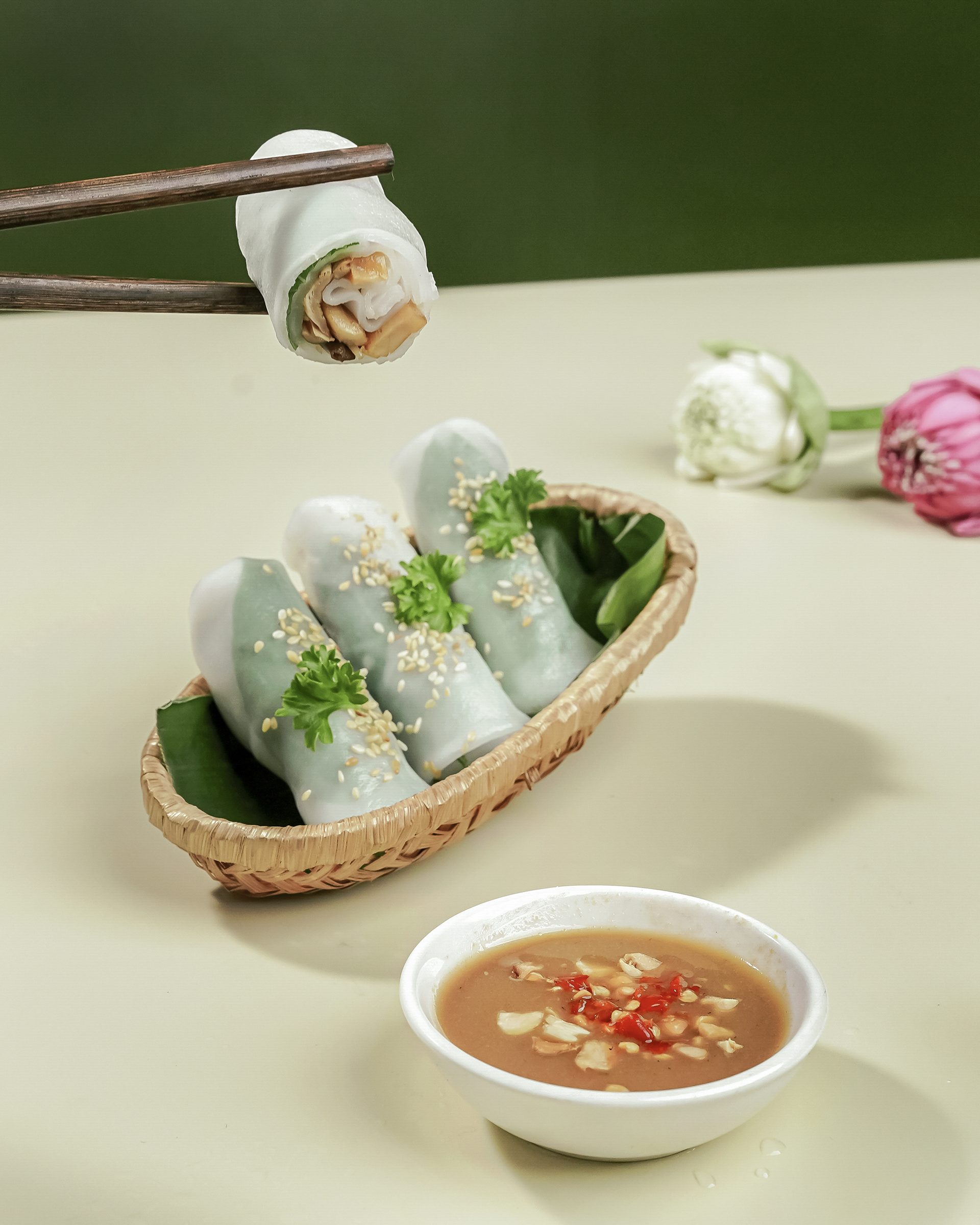 Bánh ướt cuộn rắc mè trong rổ tre, gắp bằng đũa gỗ