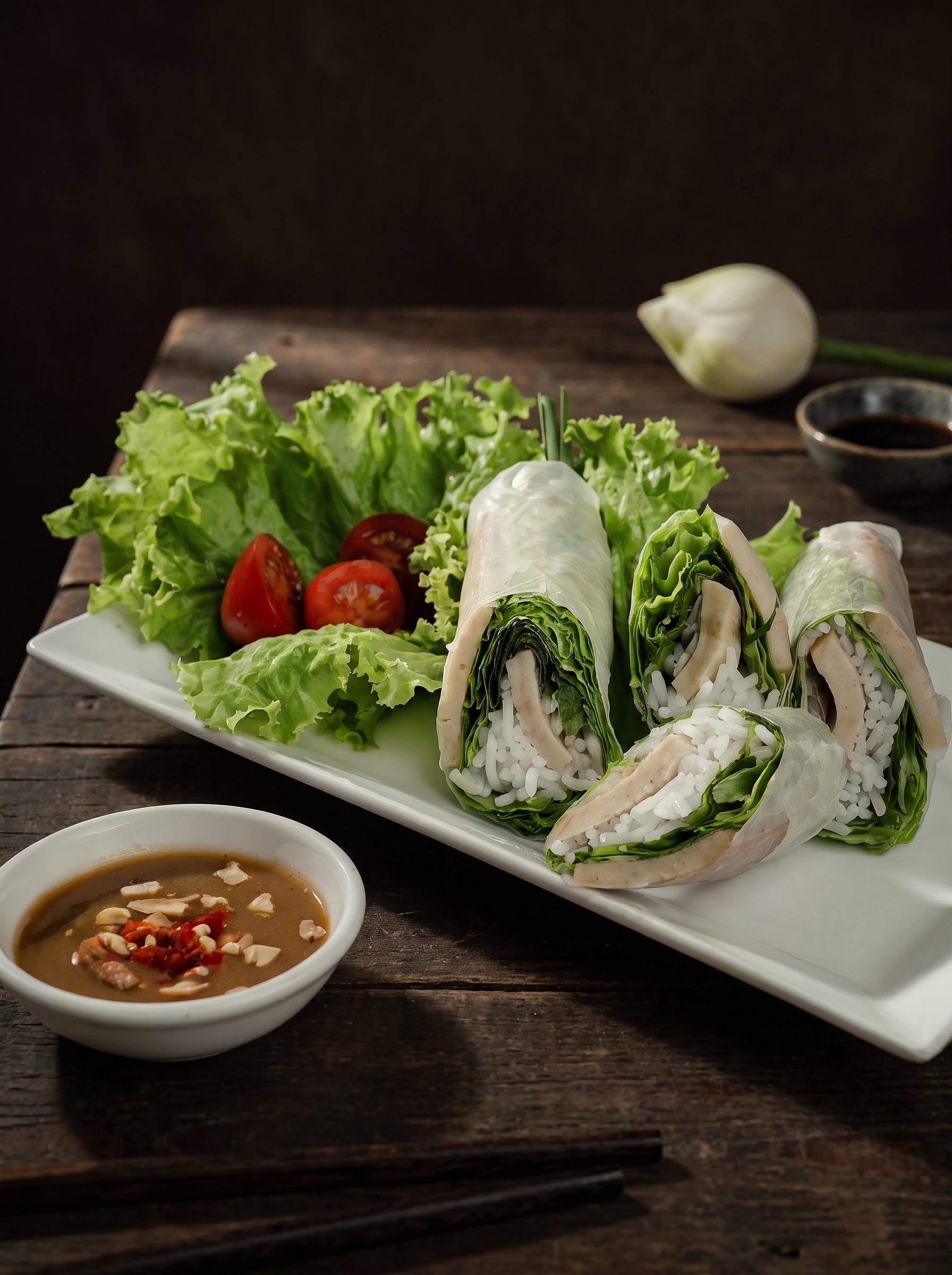 Bánh ướt cuộn trên dĩa trắng với xà lách và sốt chấm